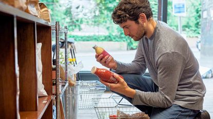 guy shopping at grocery store choosing between two juices