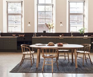 simple modern klitchen with dark cabinetry and wooden dining area in front