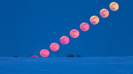 A time lapse image showing a pink to yellow full moon moving across a blue sky.