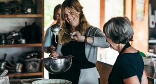 Woman laughing and holding spoon up over mixing bowl