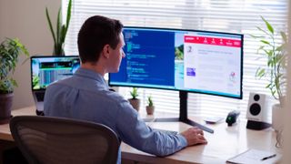 Person working on a laptop with a monitor