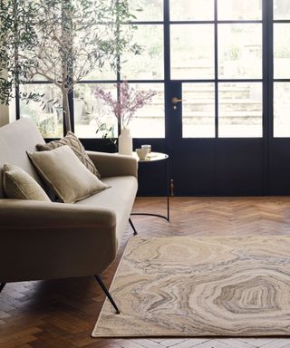 A neutral rug on a real wood floor with a neutral couch