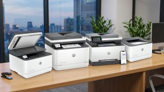 A selection of HP 3000-series laser printers on a desk in an office