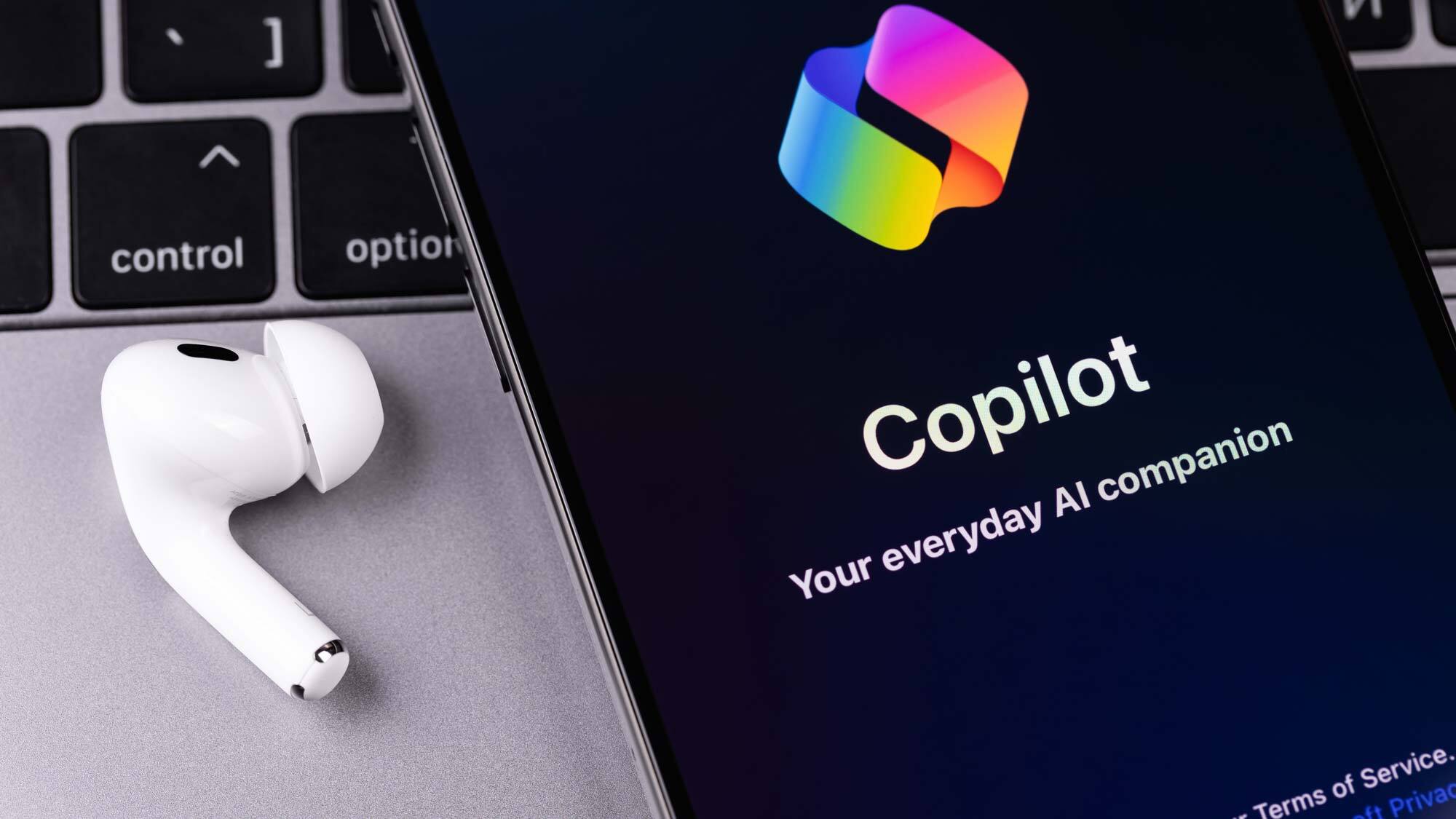 Copilot on a phone with earbuds on a desk