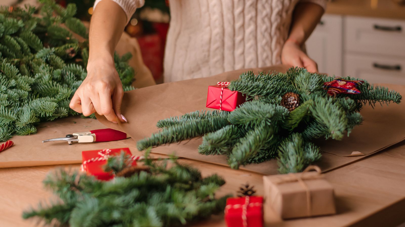 The process of making a winter bouquet of fir branches at home, packaging in kraft paper,close-up of the woman&#039;s hands.