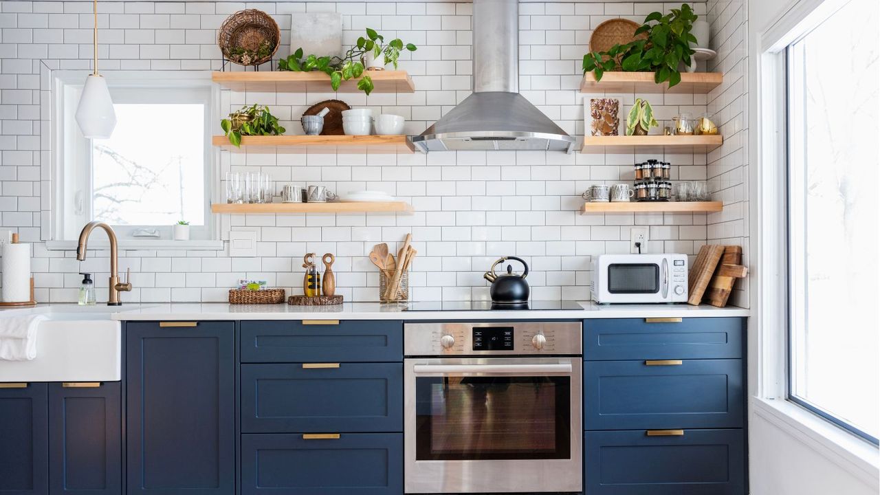 Luxury kitchen with blue lower cabinets, white counters, electric stovetop, and open shelving on white subway tiles 