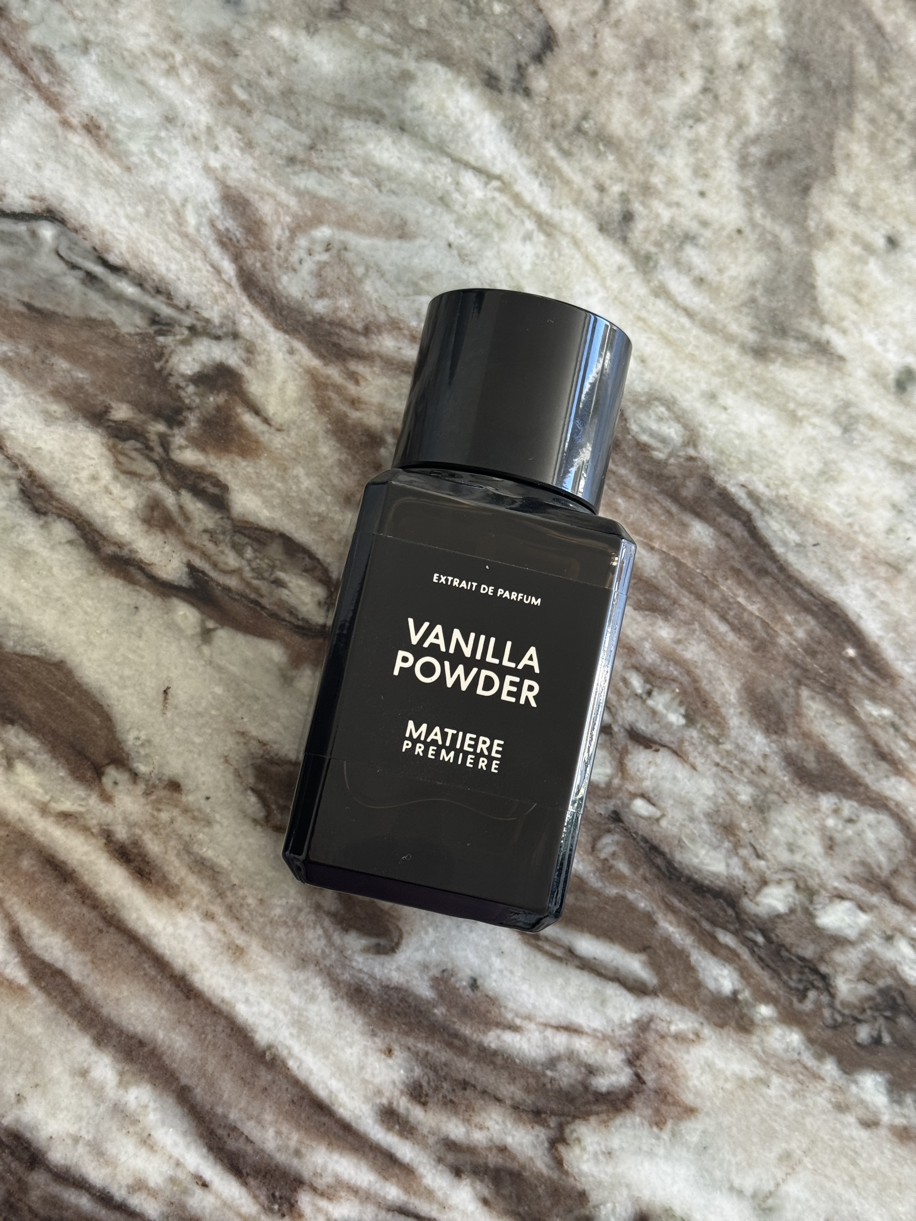 A bottle of Vanilla Powder Extrait on a marble table