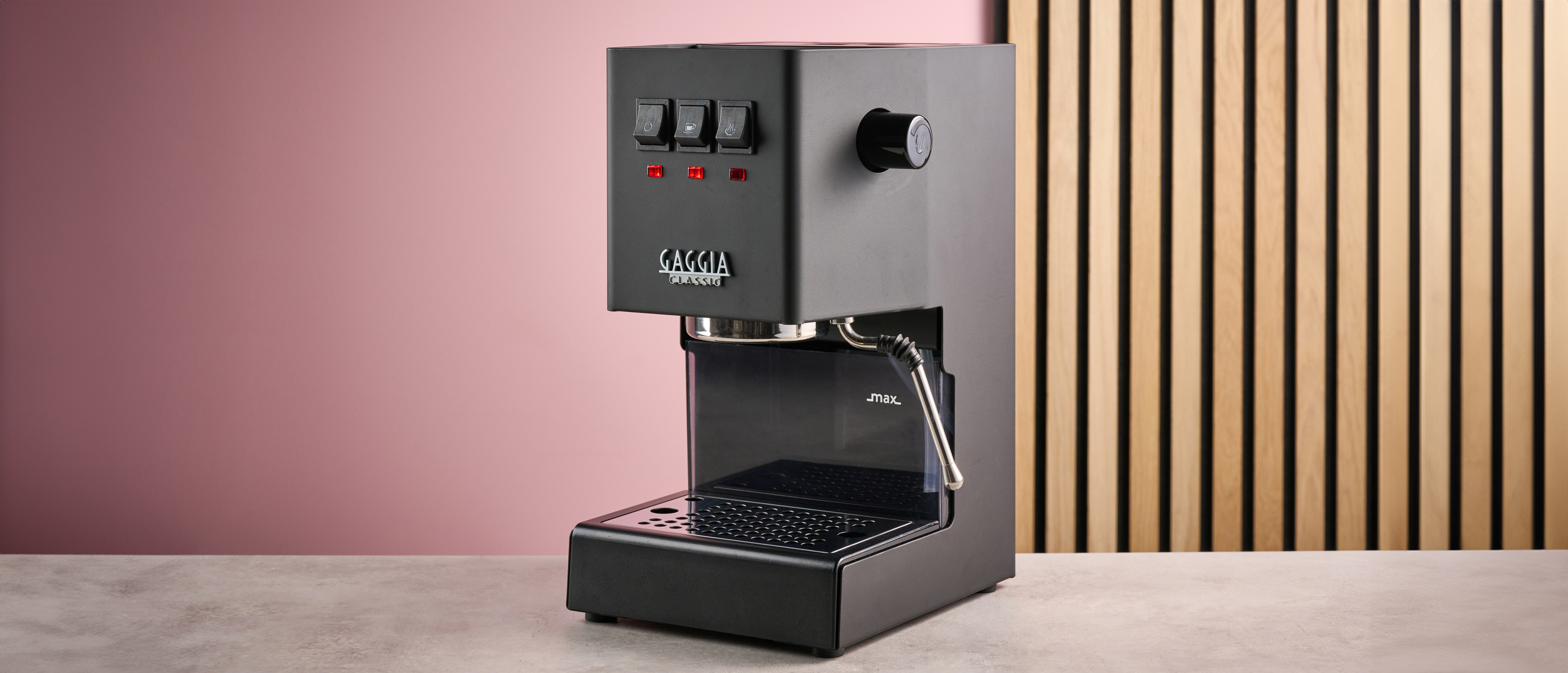 The Gaggia Classic E24 Evo Pro in front of a pink background with a slatted wooden panel.