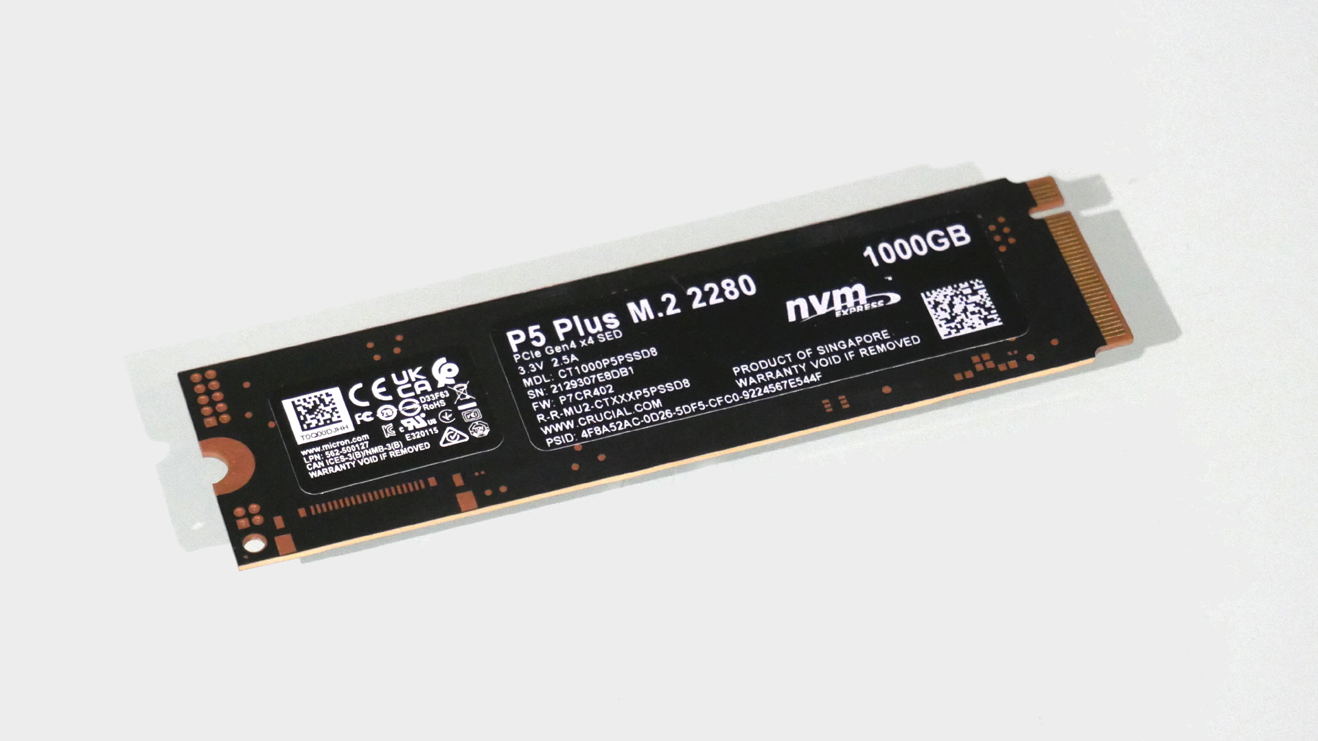 Fotografía del SSD Crucial P5 Plus de 1 TB sobre un fondo gris claro.