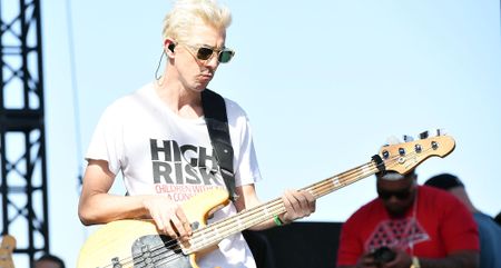 A bleached-blond Stu "Bassie" Brooks wears shades and plays bass in the bright sunshine.