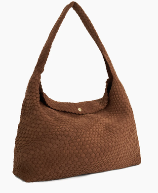 a woven bag in front of a plain backdrop