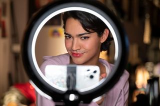 Miss Benny poses in front of a ring light and a cell phone in glamorous