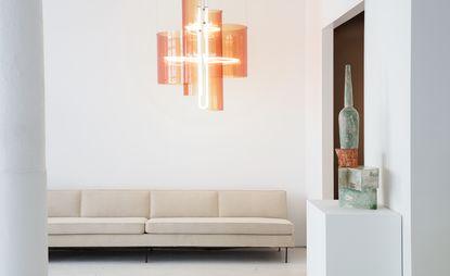 Room with white wall cream coloured sofa and hanging lights