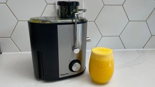 The Bagotte DB-001 juicer on a kitchen countertop with a glass of juice prepeared in the appliance