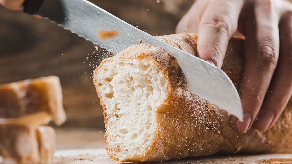 Loaf of bread being cut with a bread knife