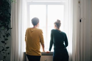 Couple looking out of window into the winter sunshine