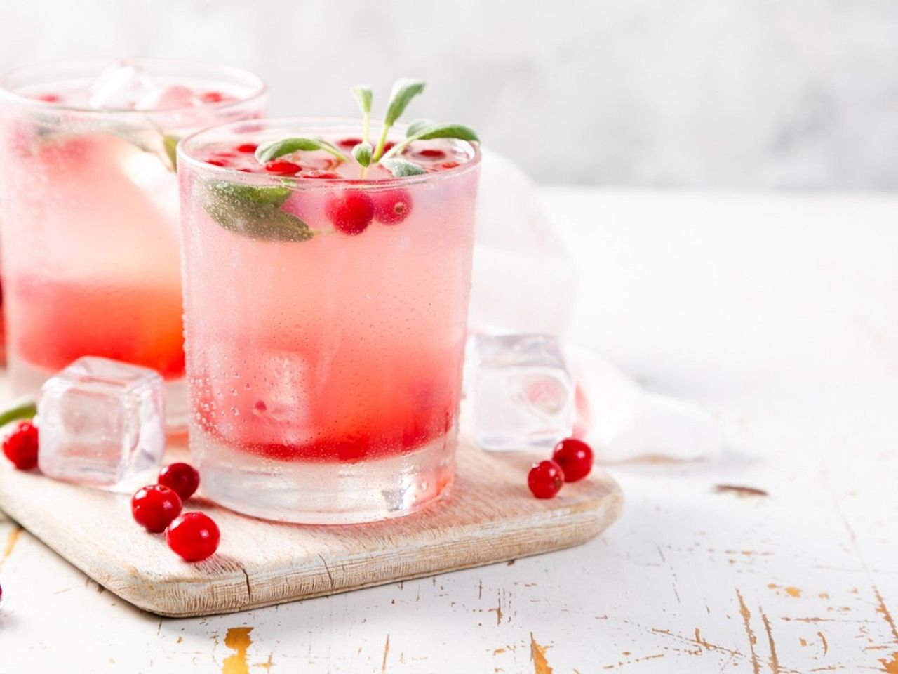 A refreshing pink cocktail with cranberries and sage leaves