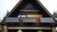 Three solar panels off a wooden framed house