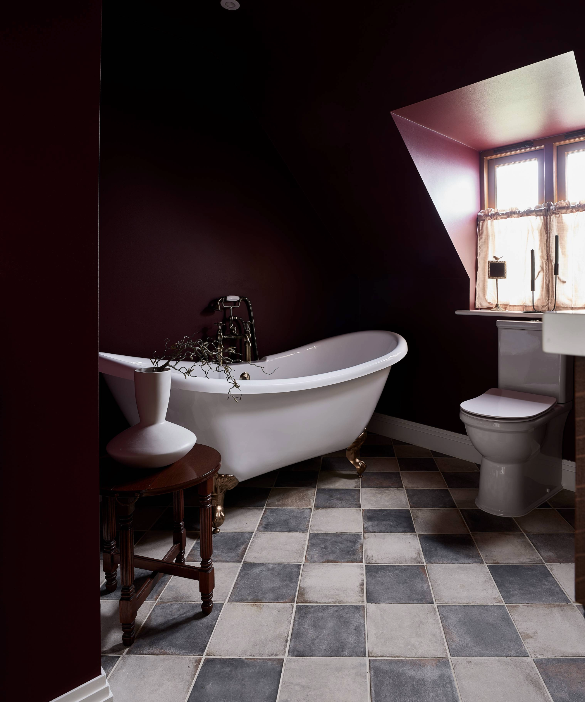 Dark bathroom idea with deep red walls, freestanding bath and chequerboard floor