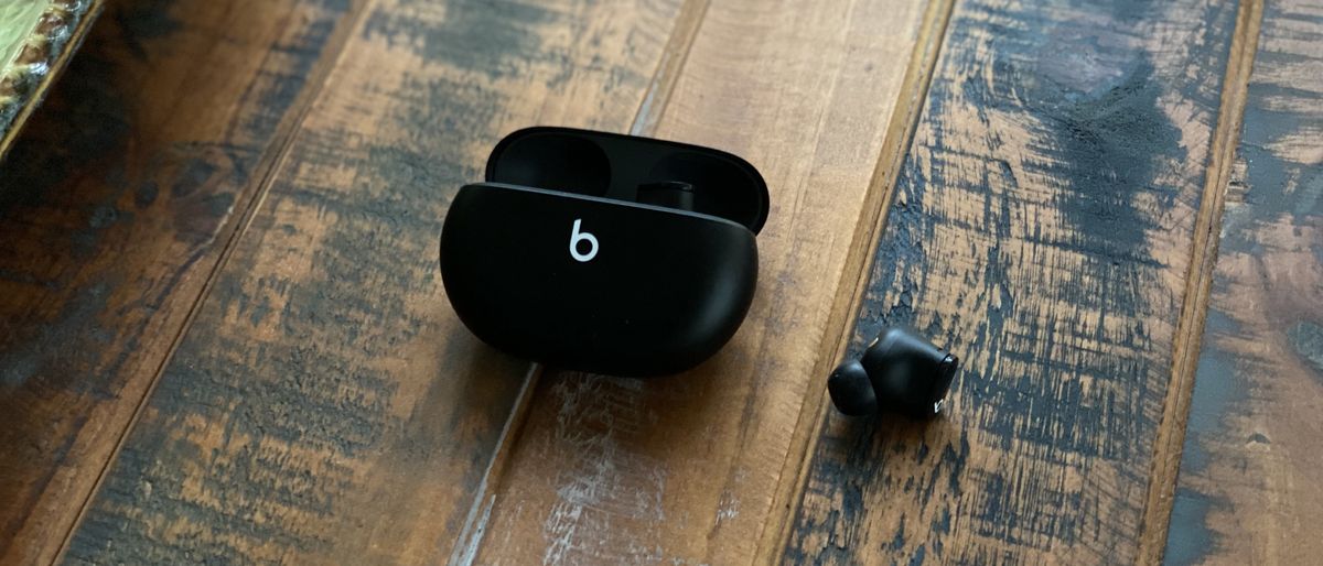 The Beats Studio Buds and their charging case in black on a wooden surface.