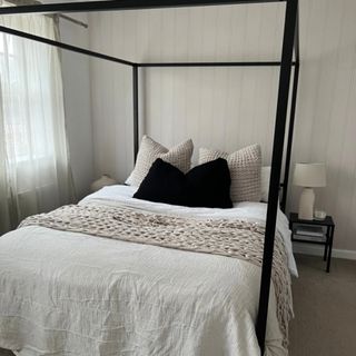 bedroom with black four poster bed and cushions