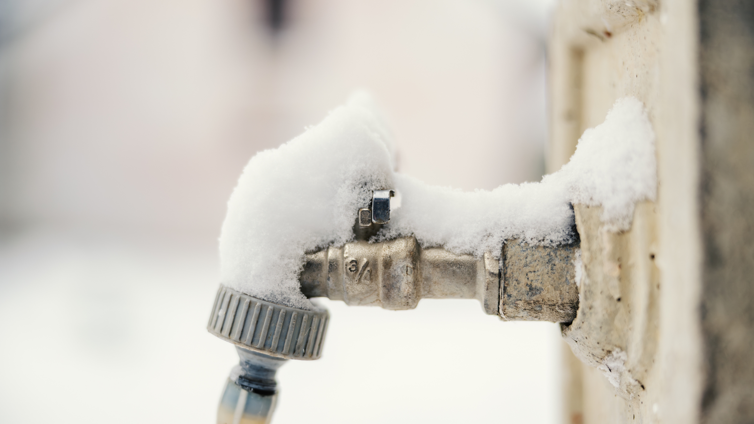 An outdoor faucet with snow in winter