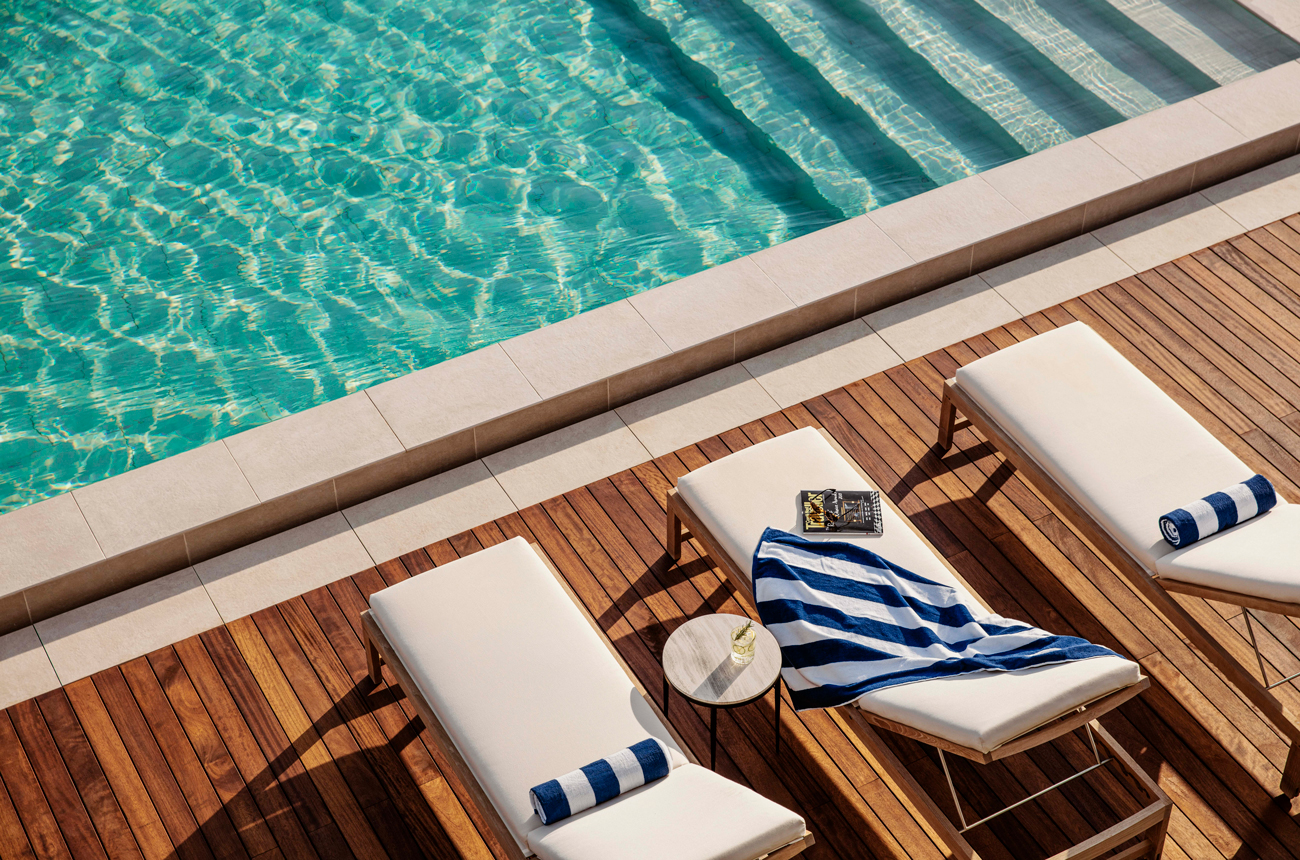 Three sun loungers next to a swimming pool