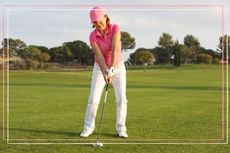a medium shot of a female golf putting in a pink top on a green on a golf course