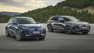 Two Audi Q6 e-tron cars in a car park in front of mountains