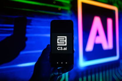 C3.ai logo on smartphone with multi-colored AI illustration in background