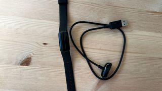 A close-up picture of a black Fitbit Luxe with charging cable
