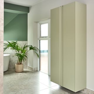 a bathroom with a bathtub, green walls, and a green floating storage cabinet