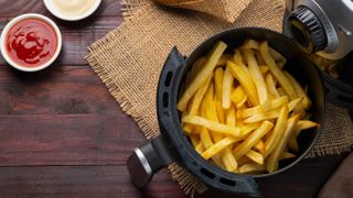 An open air fryer basket containing French fries