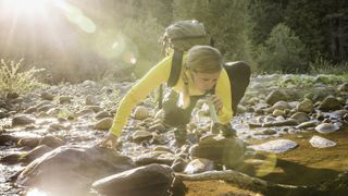 Hiker collecting water from stream