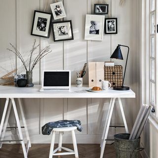 room with frames on white wall and laptop