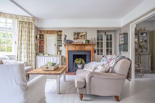 living room with cream sofas and patchwork quilt with fireplace and old dressers