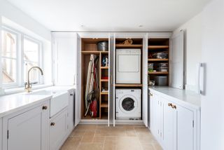 utility room design with white cabinets and space for ironing board and washer