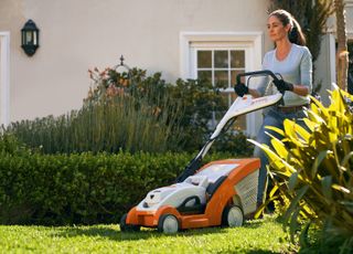 how to mow a lawn: stihl mower being used by lady in garden