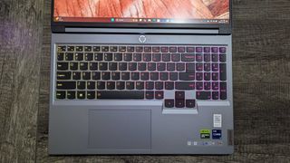 A Lenovo Legion 5i (Gen 9) gaming laptop on a desk with its display open all the way, showing the RGB-lit keyboard and touchpad.