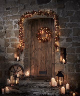 Front door lit up with garland and wreath