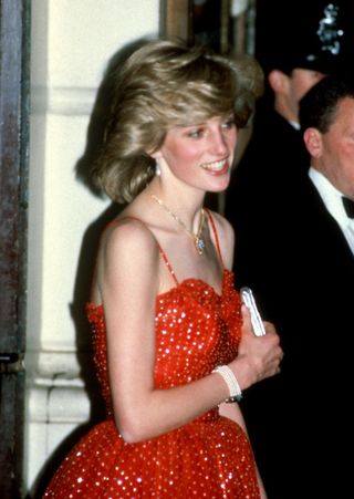 Diana, Princess of Wales, wearing a red and gold spangled chiffon gown designed by Bellville Sassoon and a gold and diamond necklace in the shape of the Prince of Wales feathers, visits the The Royal Opera House on December 8, 1982 in London, England. (Photo by Anwar Hussein/Getty Images)