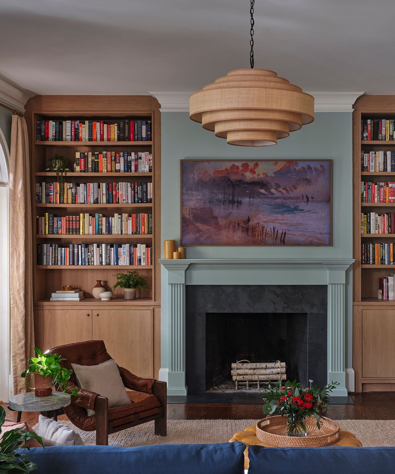 A light blue sitting room with a brown armchair and wooden built-in bookshelves