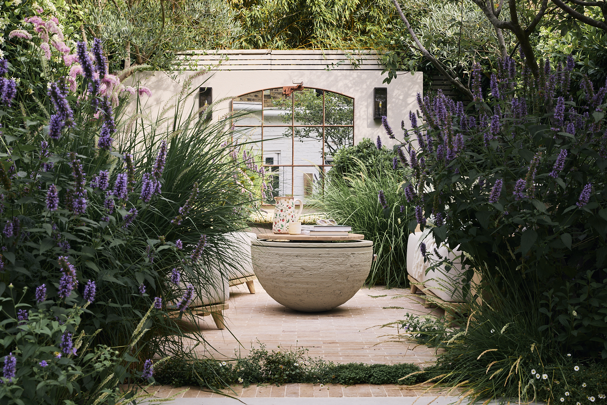 a modern garden with lush planting, purple flowers, and sculptural landscaping