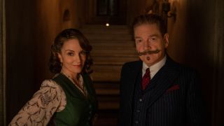 Tina Fey and Kenneth Branagh pose for a photo in a corridor lit by torches in A Haunting in Venice.