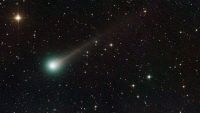 A photo of Comet Lemmon with a green glow around its nucleus and a long glowing white tail