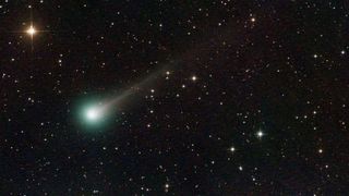 A photo of Comet Lemmon with a green glow around its nucleus and a long glowing white tail