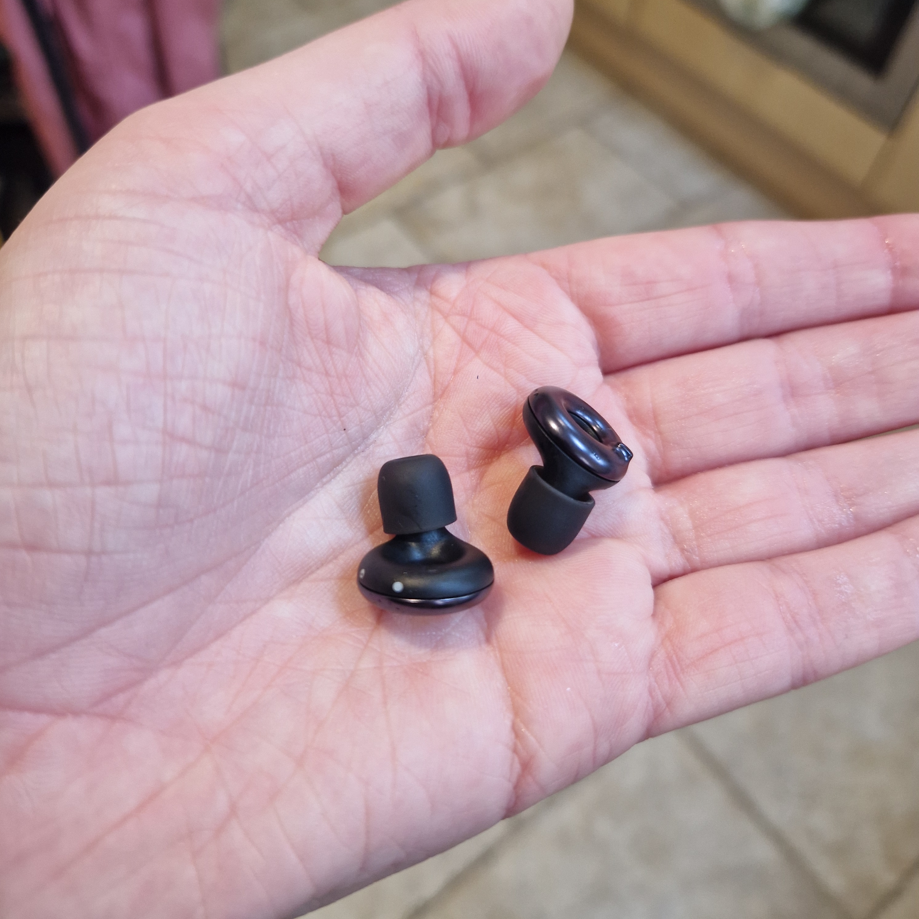 Two black earbuds in someone’s palm