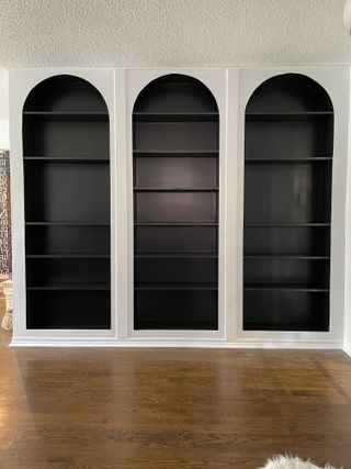 A wall of empty arched shelves with the inside of the shelves painted black