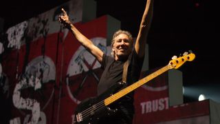 photo of Pink Floyd bass player Roger Waters raising his arms above his head and smiling from the stage at a concert in 2012