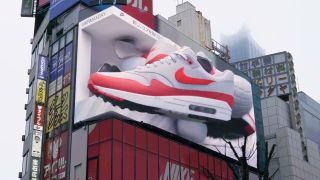 A large billboard featuring a 3D red and white Nike air max shoe